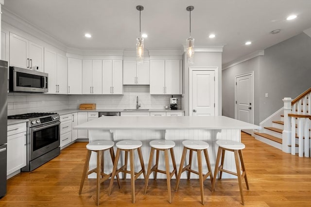 2 Rockwood Ter Unit 2, Newton, MA 02466 - kitchen with stainless steel appliances, a sink, a breakfast bar, tasteful backsplash, and ornamental molding