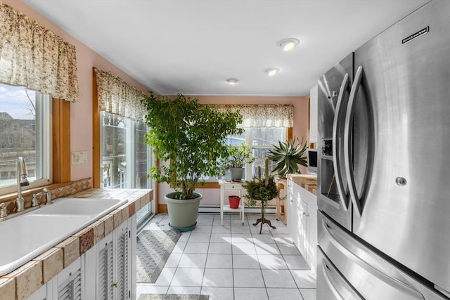 kitchen with stainless steel fridge with ice dispenser, a baseboard radiator, light countertops, white cabinetry, and a sink