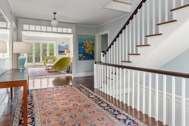 entryway with ornamental molding and dark hardwood / wood-style floors