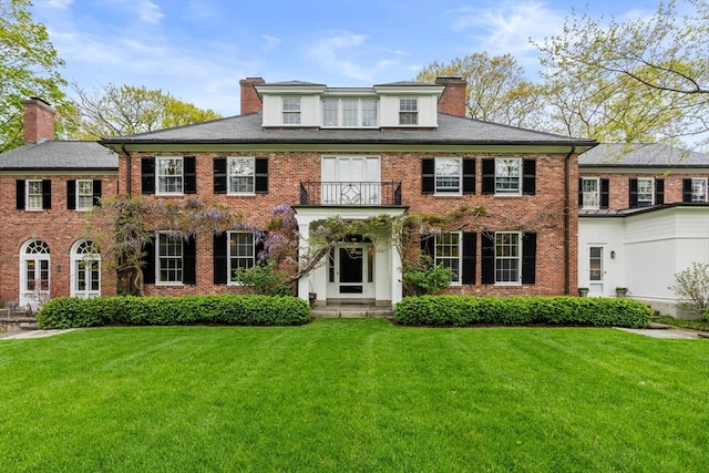 colonial inspired home with a front yard and a balcony