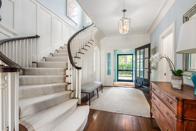 foyer entrance with crown molding and dark hardwood / wood-style flooring