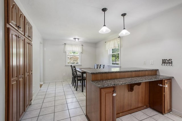 7 Cornish St, Carver, MA 02330 - kitchen featuring a peninsula, light tile patterned flooring, dark stone countertops, decorative light fixtures, and baseboards