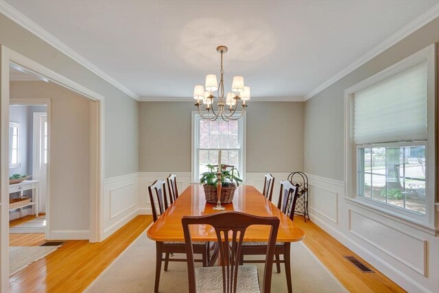 dining space featuring light wood-style floors, visible vents, crown molding, and an inviting chandelier