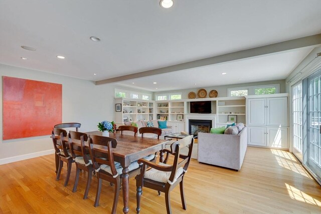 dining space featuring light wood-style flooring, a glass covered fireplace, beam ceiling, and recessed lighting