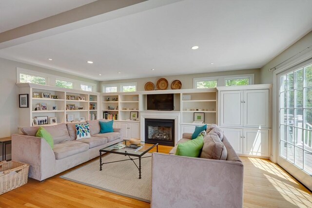 living room with light wood-style floors, recessed lighting, and a glass covered fireplace