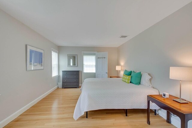 bedroom with light wood-style flooring, visible vents, and baseboards