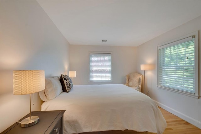 bedroom featuring light wood-type flooring, visible vents, and baseboards