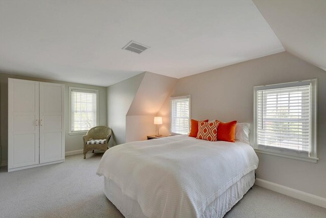 bedroom featuring light colored carpet, visible vents, vaulted ceiling, and baseboards