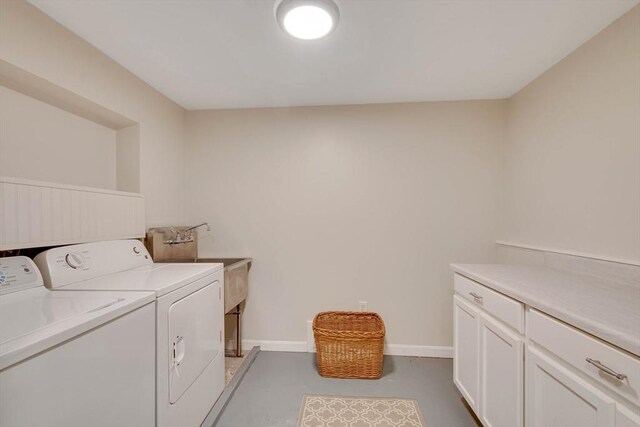 washroom with cabinet space, baseboards, and washer and clothes dryer