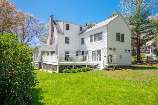 rear view of house with a deck, a lawn, and a chimney