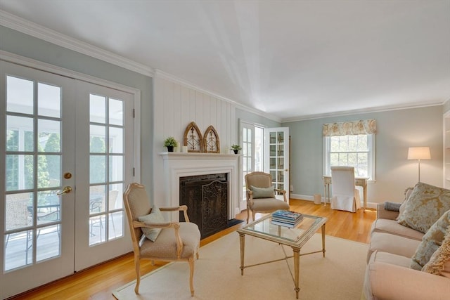 living room featuring french doors, crown molding, a fireplace with flush hearth, wood finished floors, and baseboards