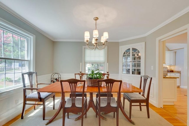 dining space featuring a healthy amount of sunlight, light wood-style flooring, crown molding, and a notable chandelier