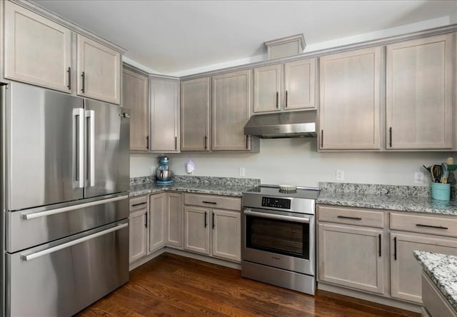 kitchen featuring dark hardwood / wood-style flooring, stainless steel appliances, and light stone counters