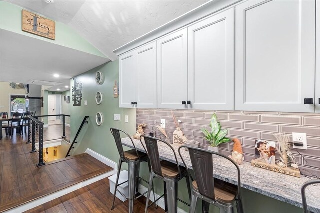 8 New Spencer Rd, Charlton, MA 01507 - kitchen with light stone countertops, tasteful backsplash, dark wood-style floors, vaulted ceiling, and white cabinetry