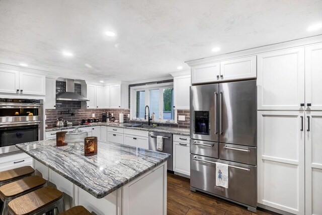8 New Spencer Rd, Charlton, MA 01507 - kitchen with appliances with stainless steel finishes, wall chimney range hood, a sink, white cabinets, and decorative backsplash