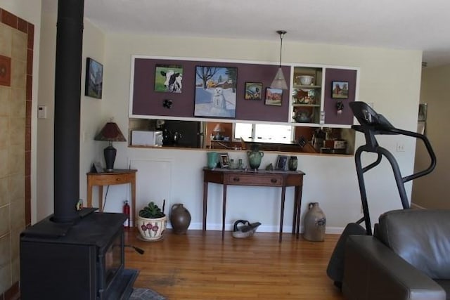 living area with a wood stove and wood finished floors