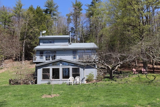 back of house featuring a lawn, metal roof, and a balcony
