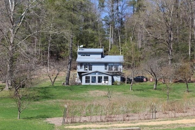 view of front of house with a view of trees, metal roof, and a front yard