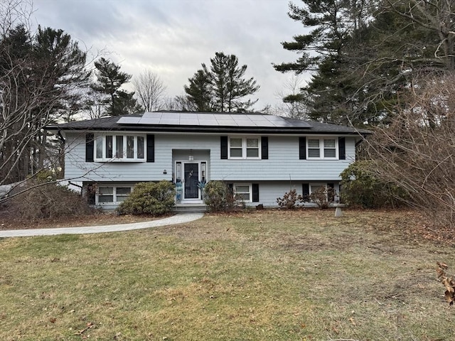 bi-level home with a front lawn and solar panels