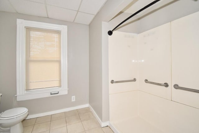 bathroom with tile patterned flooring, a shower, a paneled ceiling, and toilet