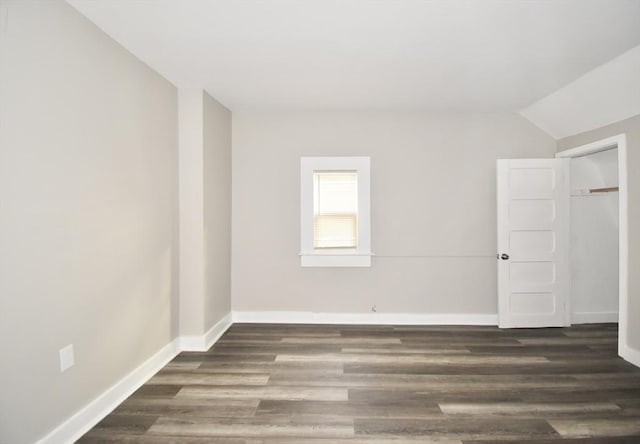 unfurnished room featuring dark hardwood / wood-style floors and vaulted ceiling