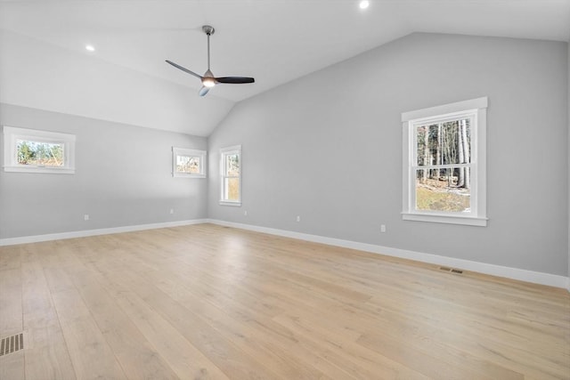 empty room featuring plenty of natural light, vaulted ceiling, and light hardwood / wood-style flooring