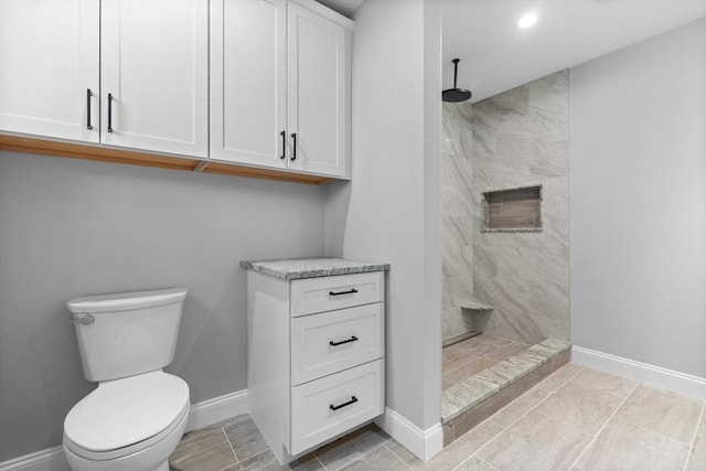 bathroom featuring a tile shower and toilet