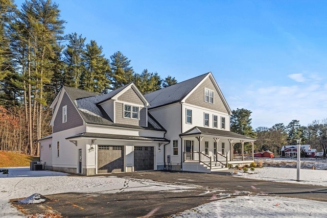 view of front property featuring a porch, a garage, and central air condition unit