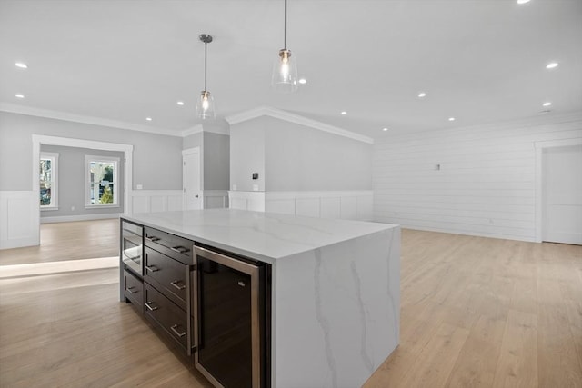 kitchen featuring light stone countertops, light wood-type flooring, ornamental molding, decorative light fixtures, and beverage cooler