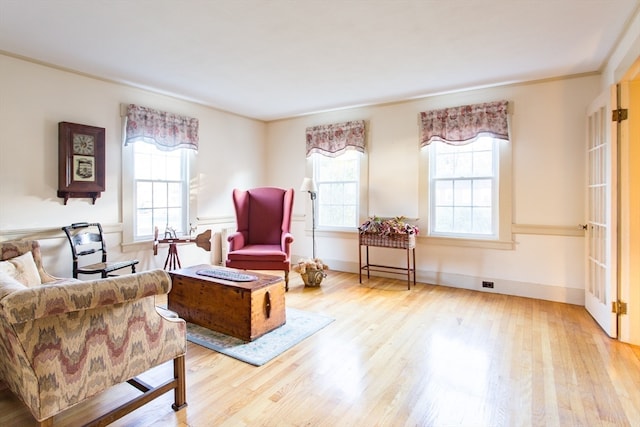 living area with light hardwood / wood-style floors and crown molding