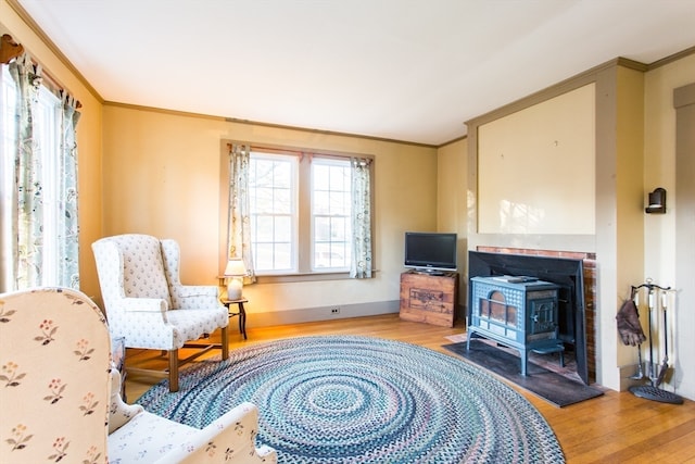 living area featuring a wood stove, light hardwood / wood-style flooring, and crown molding