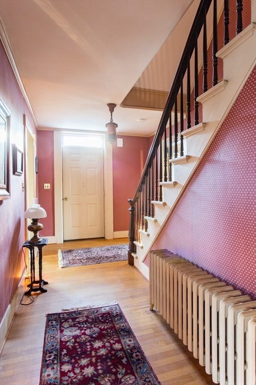 entrance foyer with radiator, crown molding, and light hardwood / wood-style floors