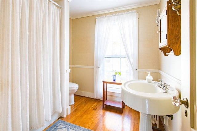 bathroom with wood-type flooring, toilet, and ornamental molding