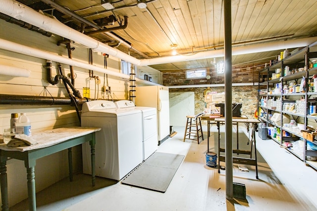 basement with washing machine and dryer, white refrigerator, and a workshop area