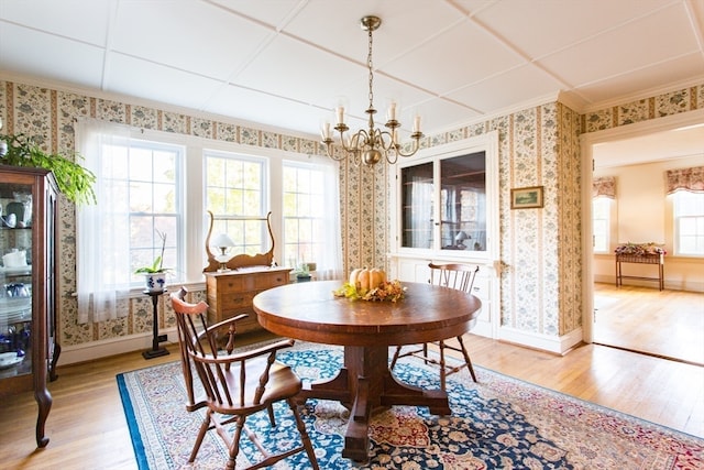 dining space featuring a healthy amount of sunlight, light wood-type flooring, and a notable chandelier