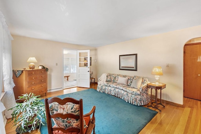 890 Westford St, Lowell, MA 01850 - living room featuring arched walkways, a baseboard radiator, and wood finished floors