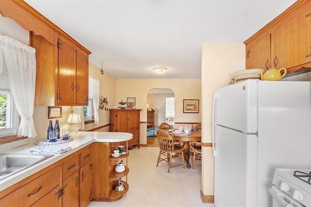 890 Westford St, Lowell, MA 01850 - kitchen featuring arched walkways, white appliances, light countertops, light flooring, and brown cabinetry