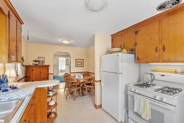 890 Westford St, Lowell, MA 01850 - kitchen with white appliances, arched walkways, light countertops, and brown cabinetry
