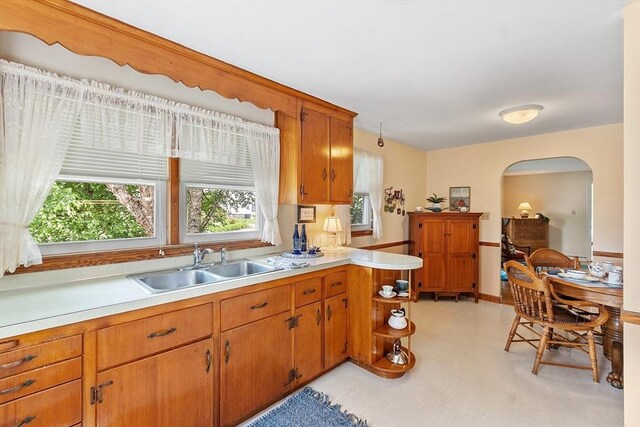 890 Westford St, Lowell, MA 01850 - kitchen featuring arched walkways, light countertops, a peninsula, brown cabinets, and light flooring