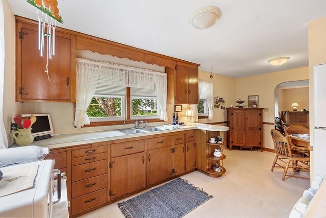 890 Westford St, Lowell, MA 01850 - kitchen with range, light countertops, arched walkways, a peninsula, and brown cabinetry