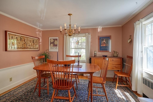 dining area with radiator heating unit, an inviting chandelier, ornamental molding, and a healthy amount of sunlight