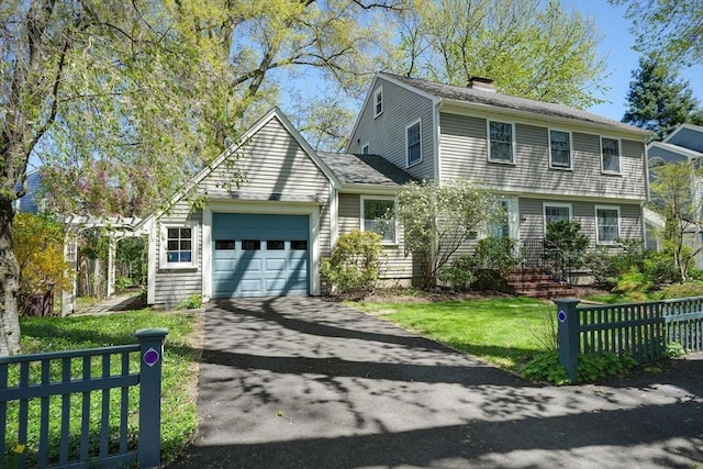 colonial house featuring a garage, fence, a chimney, and aphalt driveway