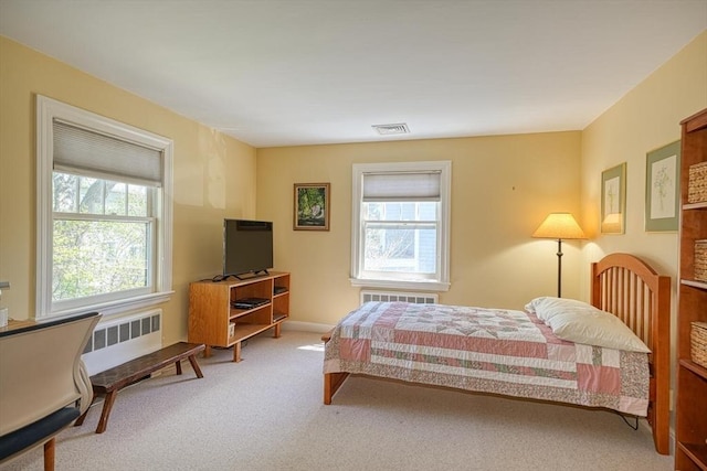 carpeted bedroom featuring radiator heating unit, baseboards, and visible vents