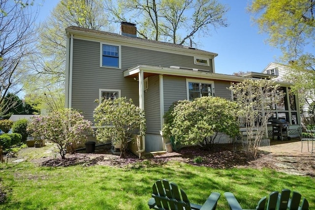 back of property with a lawn and a chimney