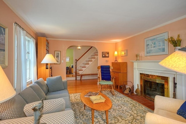 living area with arched walkways, ornamental molding, stairway, and a tile fireplace