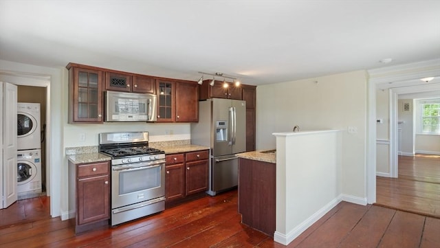 141 State St Unit 2, Newburyport, MA 01950 - kitchen with appliances with stainless steel finishes, stacked washer / dryer, dark wood-style flooring, and glass insert cabinets