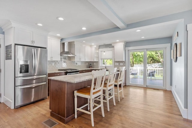 37 Gorham St, Chelmsford, MA 01824 - kitchen with appliances with stainless steel finishes, wall chimney range hood, light wood-style flooring, backsplash, and beamed ceiling