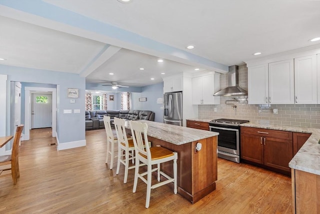 37 Gorham St, Chelmsford, MA 01824 - kitchen with wall chimney range hood, stainless steel appliances, light wood-style floors, beamed ceiling, and tasteful backsplash