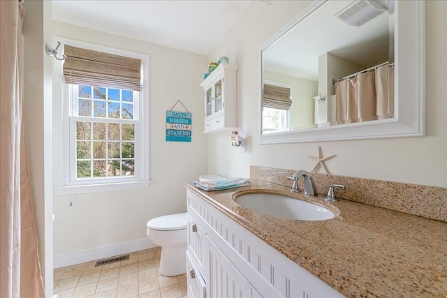 bathroom with baseboards, vanity, toilet, and visible vents