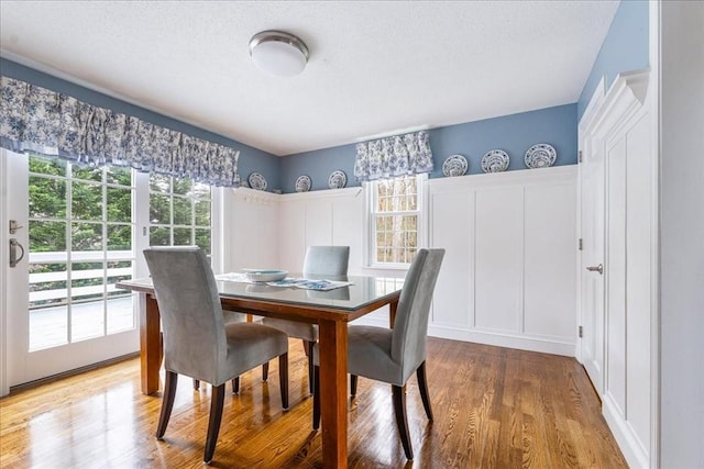 dining area with a textured ceiling, a wealth of natural light, and light wood-type flooring